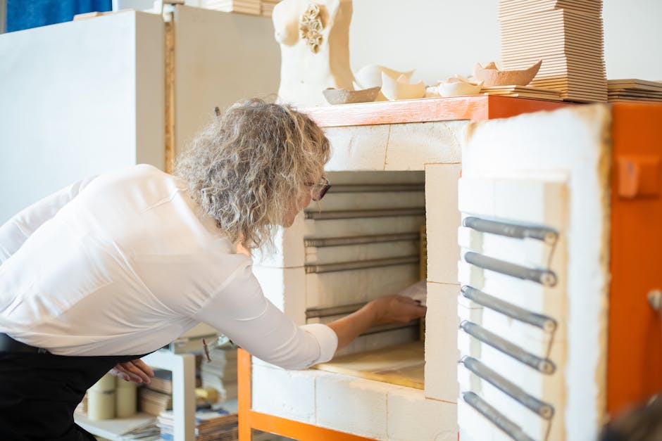 A senior woman using a kiln in a pottery studio. Indoor scene with clay art.