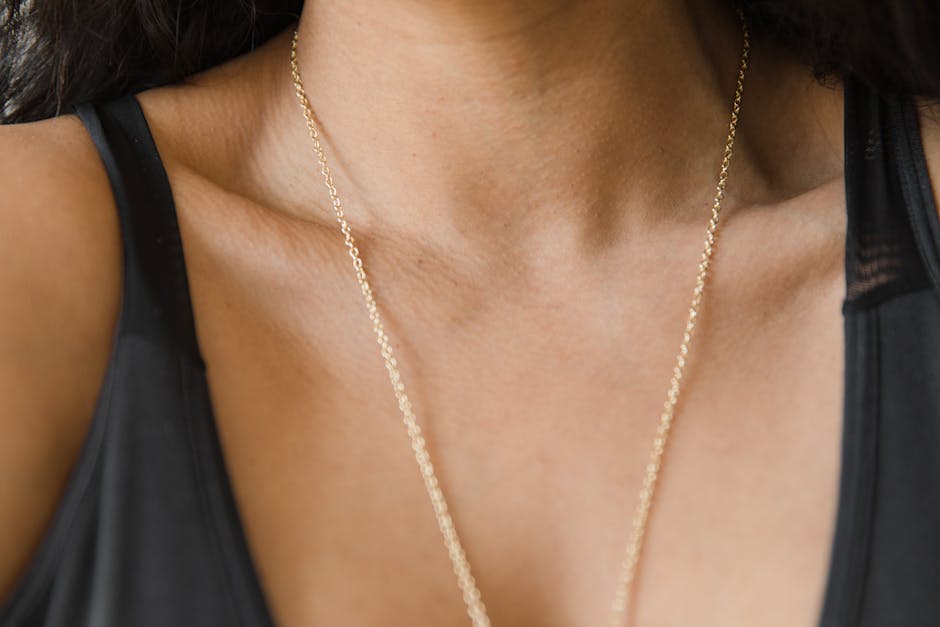 Close-up of a gold necklace resting on a woman's collarbone in natural lighting.