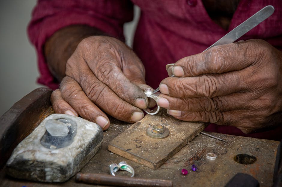 Close-up of a skilled artisan crafting a silver ring by hand at a workshop desk.