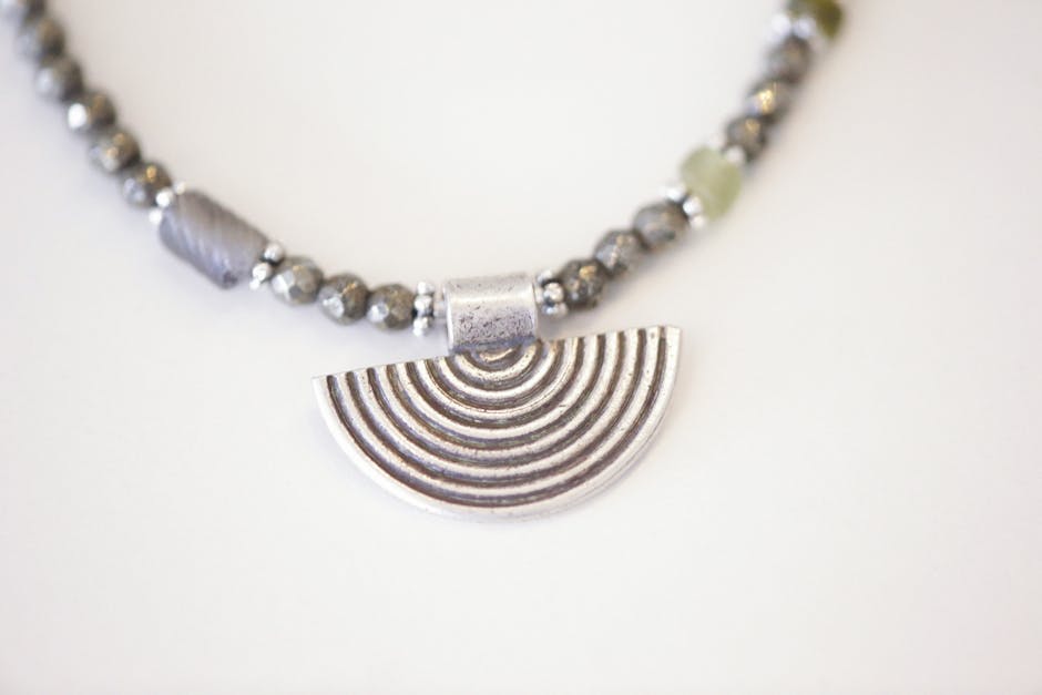 Close-up of a stylish silver beaded necklace featuring a unique half-circle pendant design.