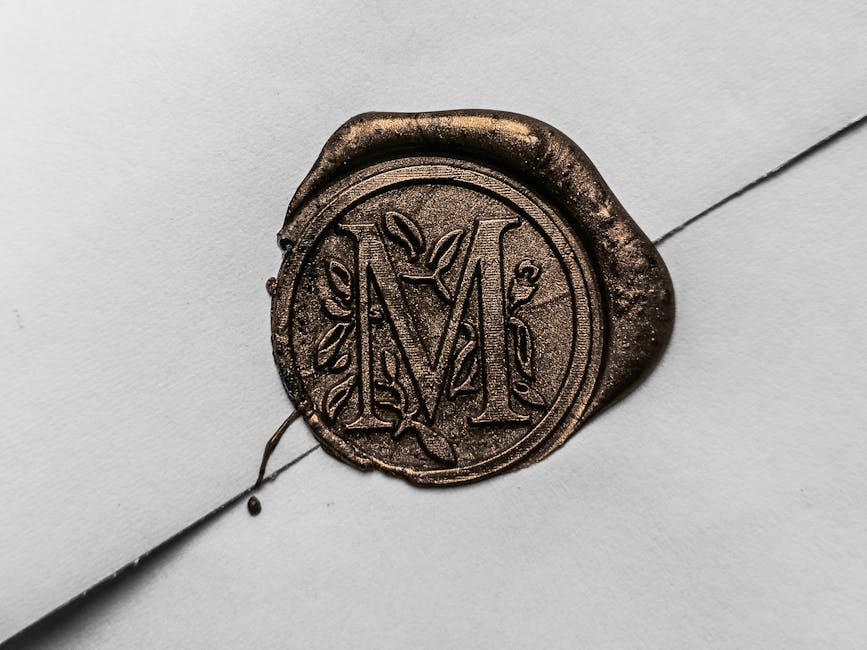 Close-up of a gold wax seal with letter 'M' on a white envelope, showcasing vintage elegance.